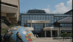 Modern National Archives building with glass facade and mosaic globe sculpture, clear sky background.