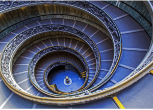 Spiraling staircase with decorative railings and golden accents, viewed from above.