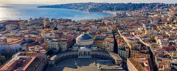 Aerial view of a coastal city with a neoclassical building, dense urban area, and bay.