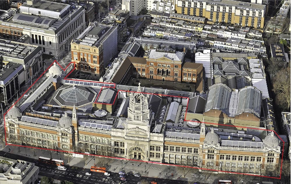 Aerial view of a large, historical building complex outlined in red, surrounded by urban structures.