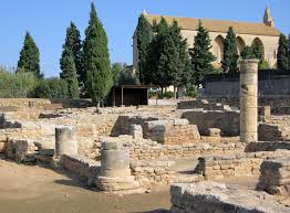 Ancient stone ruins with columns and walls, historic church, trees, blue sky in the background