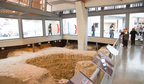 Archaeological excavation site in a modern structure with large windows and informational displays.