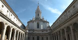 Architectural structure with dome, arches, columns in courtyard, clear sky with scattered clouds.