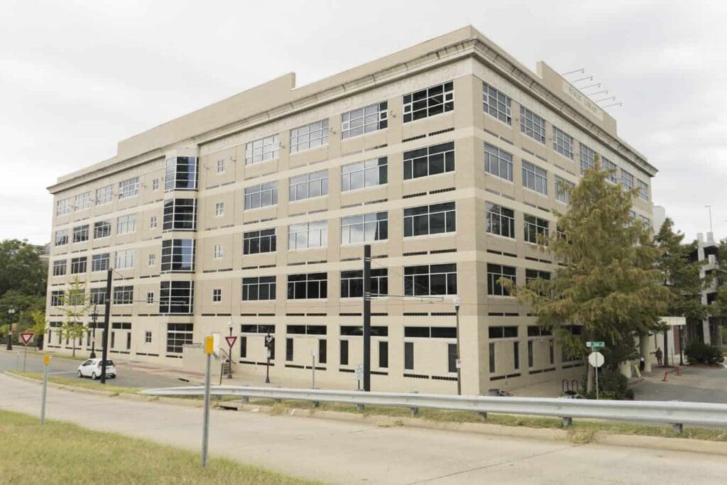 Beige modern multi-story building with large windows, identified as a public library at an intersection.