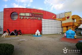 Brightly colored curved building with "Animation" and cartoon sculptures in front, open space around.