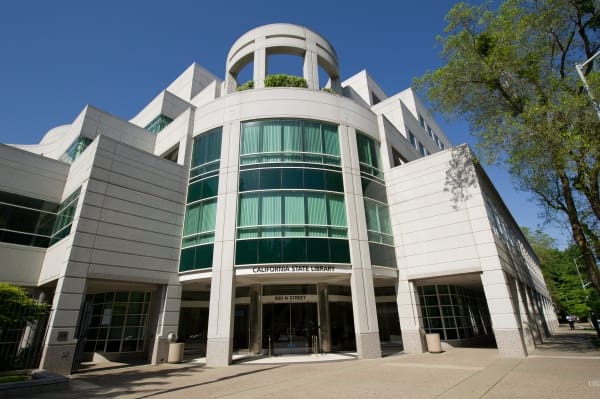 Modern multi-story building labeled "California State Library" with large windows and circular roof.