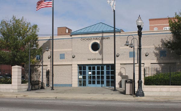 Chicago Public Library Near North Branch beige facade, blue accents, circular window, flagpoles, sidewalk.