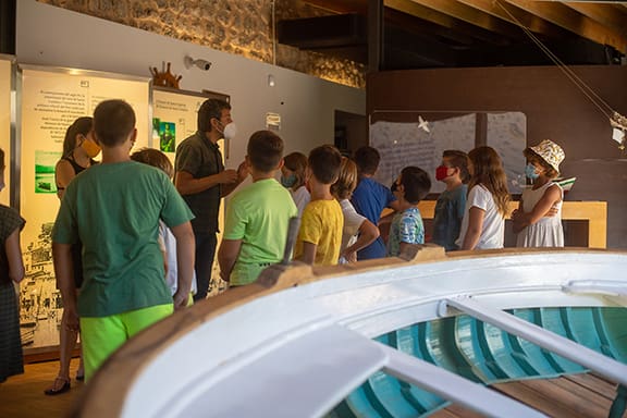 Children with an adult guide on an educational tour inside a museum with a nautical theme.