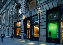 Classic stone façade building with arched windows, modern glass storefronts, and people on the sidewalk
