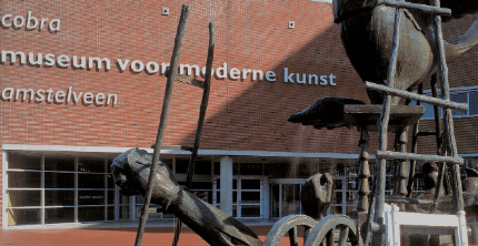 Entrance of Cobra Museum for Modern Art in Amstelveen with distinctive sculpture and brick facade.