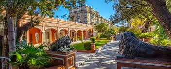 Well-maintained courtyard with greenery, lion statues, and historic architecture under blue sky