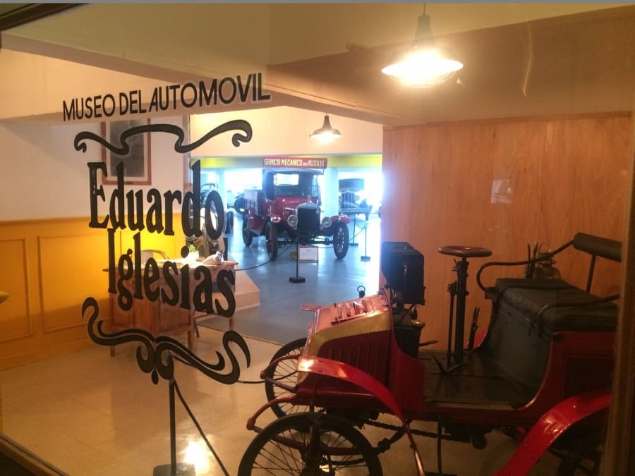 Entrance to Eduardo Iglesias Car Museum with vintage automobiles displayed behind glass.