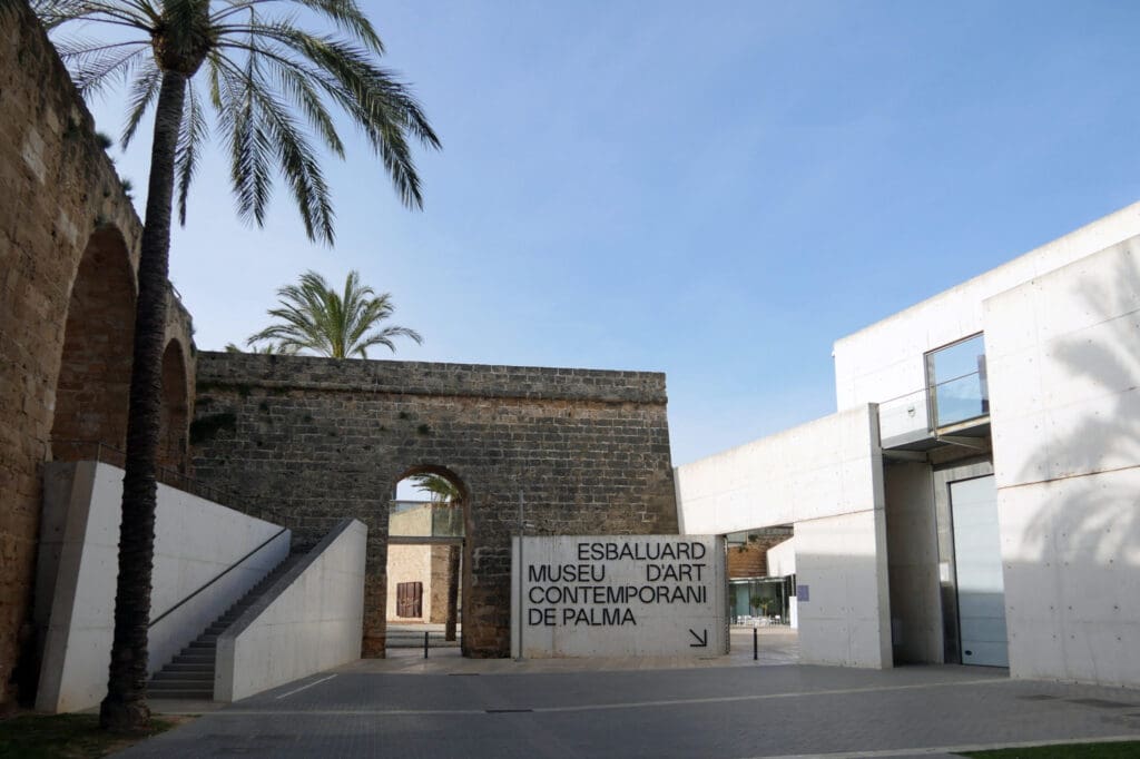 Es Baluard Museu d'Art Contemporani entrance with stone walls, concrete structures, and palm trees.