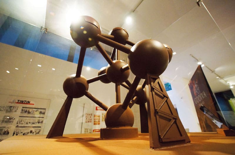 Model of a geometric structure with spheres and rods in a museum display, Tintin and Godiva signs visible.