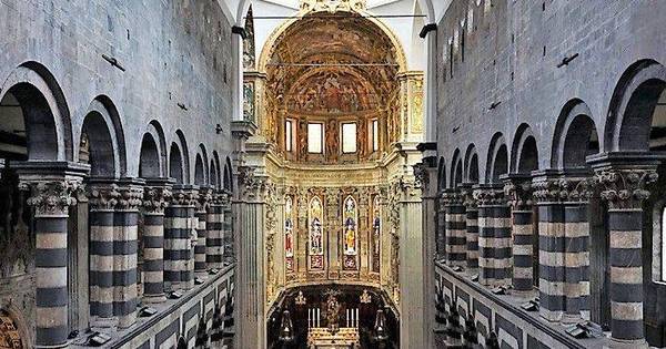 Interior of a grand cathedral with central aisle, arches, columns, frescoes, stained glass, and altar.