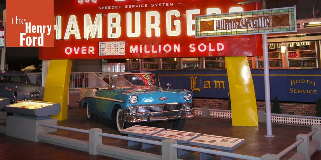 Exhibit at The Henry Ford museum featuring a vintage car and retro hamburger advertisement sign.