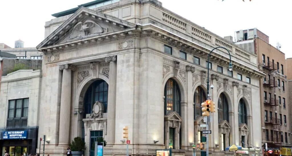 Historic building with arched windows, stone carvings, and columns near a veterinary hospital.