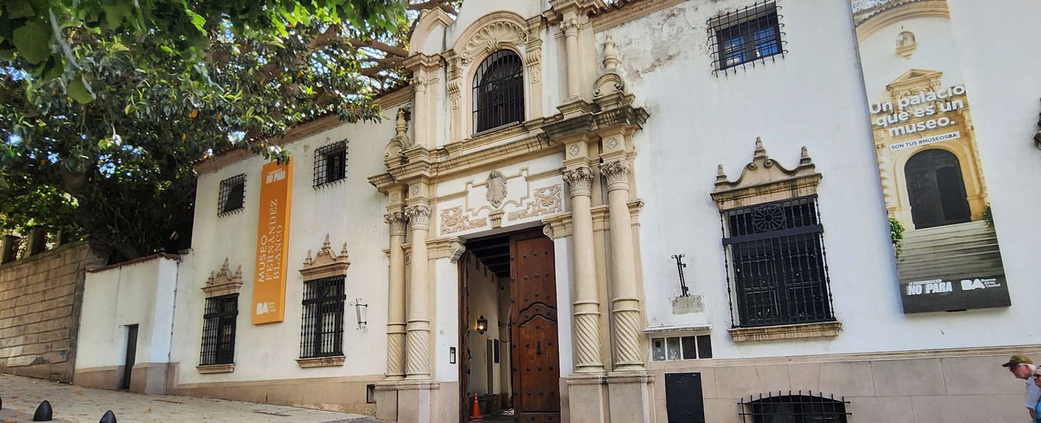 Historic building with ornate pillars and arches, Museo Larreta, featuring exhibit banners and a large door.