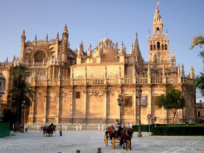 Historic cathedral with intricate carvings, tall spires, horse-drawn carriages, and clear sky