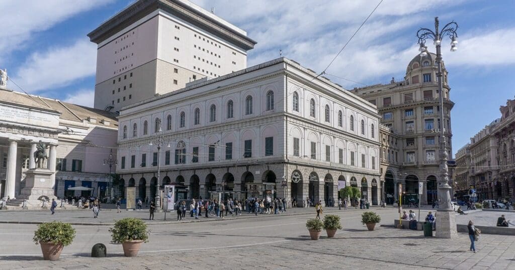Urban square with historic and modern buildings, pedestrians, a statue, streetlights, and potted plants.