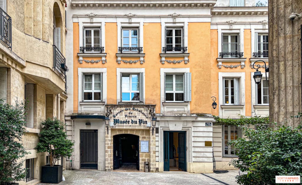 Historical mustard-colored building with white window frames, arched entrance sign reading "Musee du Vin".