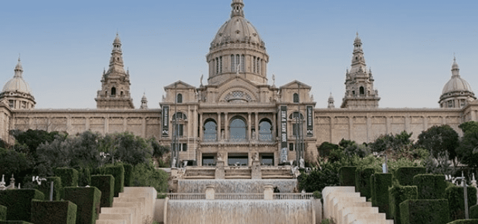 Historic stone building with large and small domes, garden terraces, and cascading water feature.