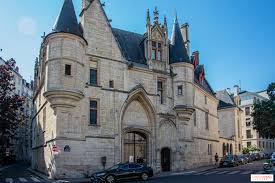 Historic stone building with pointed towers, arched windows, main entrance, street corner view