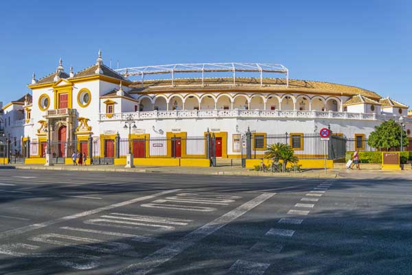 Historic yellow and white building with arched windows, ornate entrance, and pedestrians.