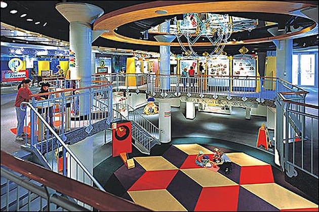 Indoor children's play and learning center with colorful flooring, exhibits, stairs, and activities.