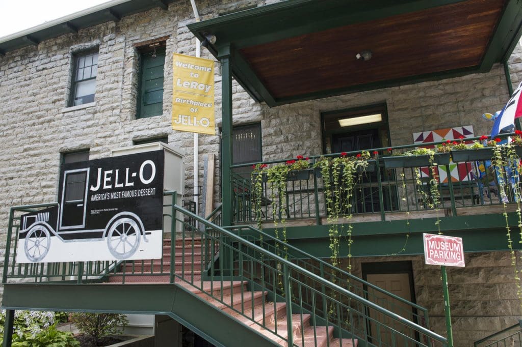 Stone building with green metal staircase, signs for Jell-O museum in LeRoy, birthplace of Jell-O.