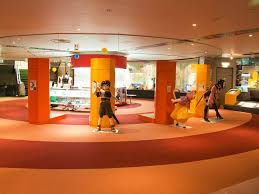 Mannequins in various poses in a colorful indoor exhibit with circular floor patterns.