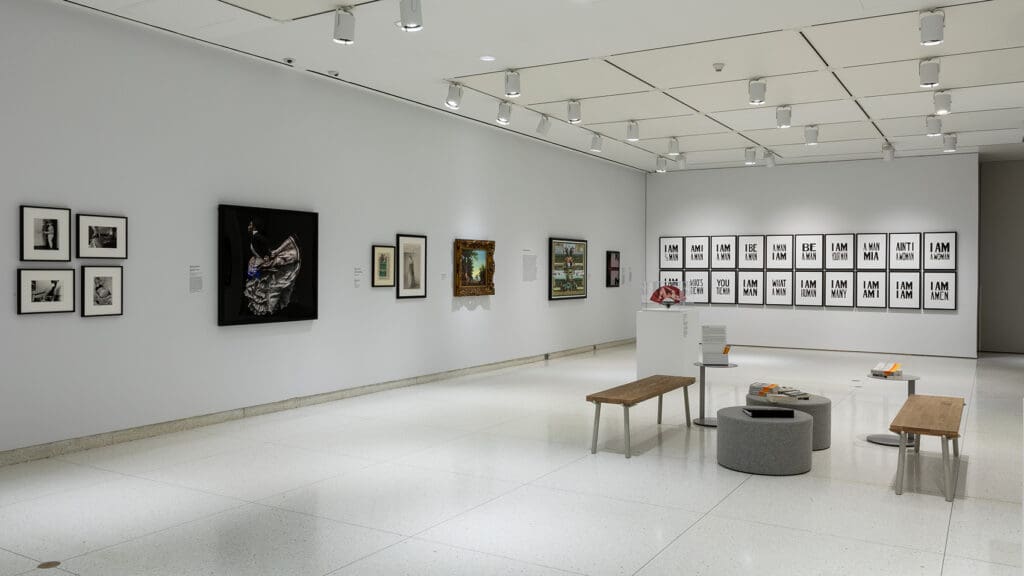 Modern art gallery with various framed artworks, spotlights, minimalist design, benches in center
