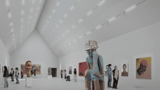 Modern art gallery with sculptures and paintings in a spacious, well-lit room; visitors viewing exhibits.