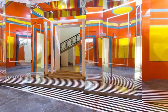 Bright modern interior with geometric patterns, mirrors, vibrant orange, yellow, blue, red elements.