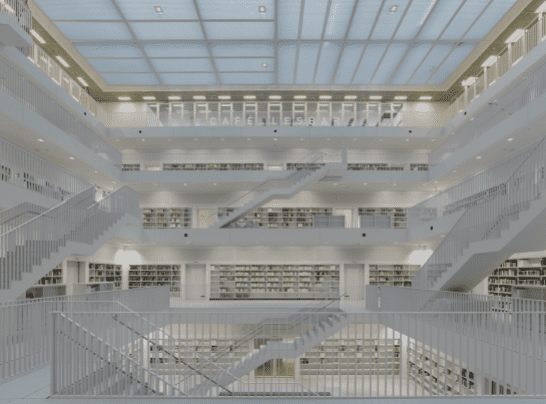 Modern, multi-level library interior with central atrium, translucent ceiling, and white, minimalist design.