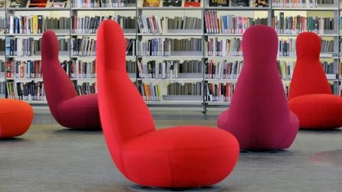 Modern library with red and purple contemporary chairs and shelves filled with books