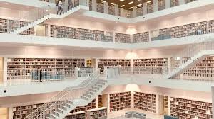 Modern multi-level library with white interior, numerous book-filled shelves, and people reading.