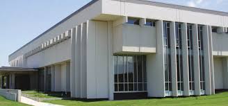 Modern two-story building with vertical elements, large windows, and landscaped lawn in foreground.