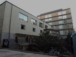 Multi-story residential buildings with windows, metal fence, and parked bicycle near the fence.