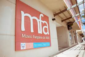 Exterior of Museo Fueguino de Arte with large "mfa" sign, sidewalk, and city setting.