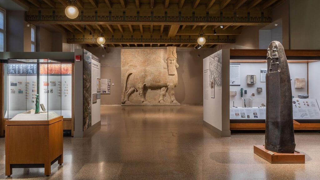 Museum exhibit featuring a large relief sculpture of a mythical creature with display cases around.