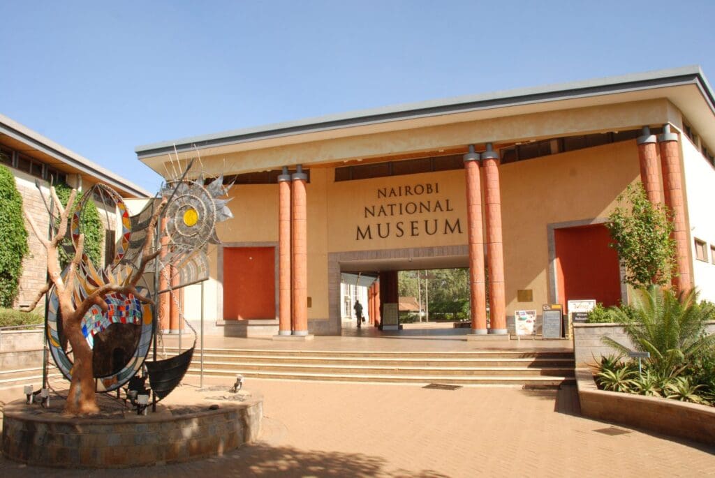 Entrance of Nairobi National Museum with red columns, sculpture, prominent sign, and well-kept surroundings