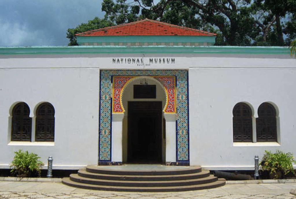 National Museum building with white walls, red-tiled roof, arched windows, and colorful entrance arch.