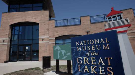 Entrance of the National Museum of the Great Lakes with a sign and lighthouse structure nearby