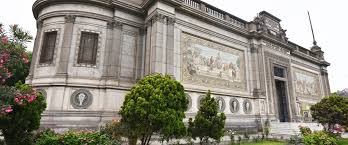 Ornate building with classical architecture, murals, carvings, and landscaped greenery.