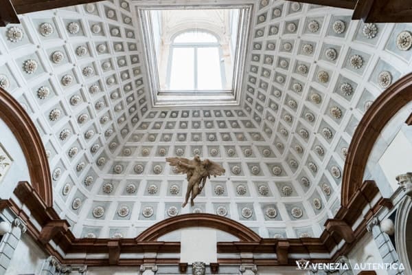 Intricately designed domed ceiling with skylight, suspended angel sculpture, and classical details.