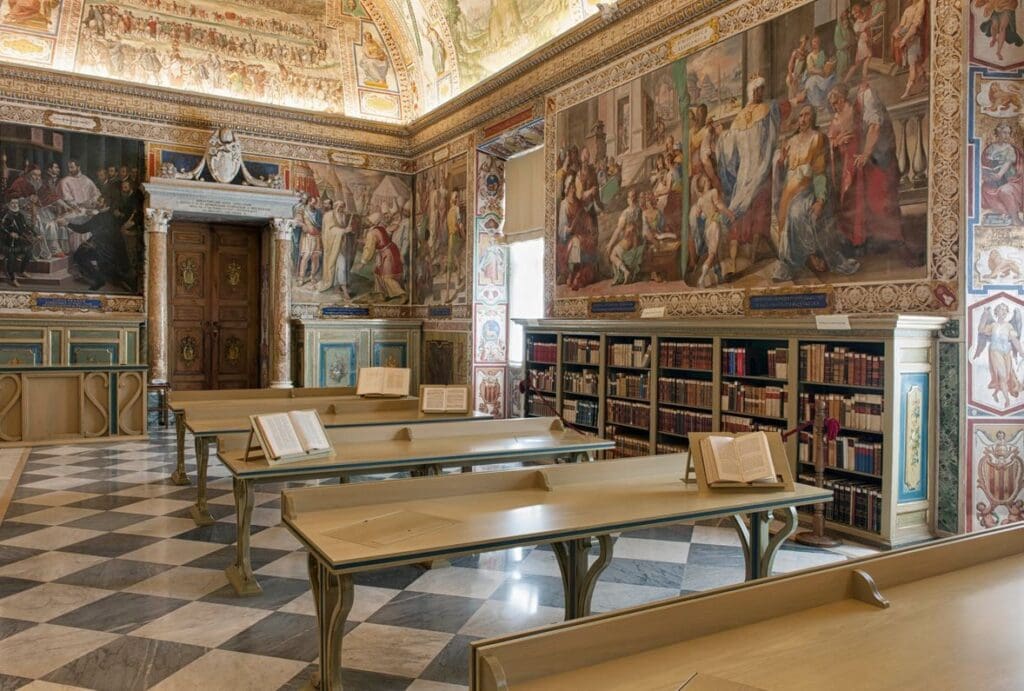 Ornate library with frescoes, wooden tables, bookshelves filled with volumes, and a checkerboard floor.