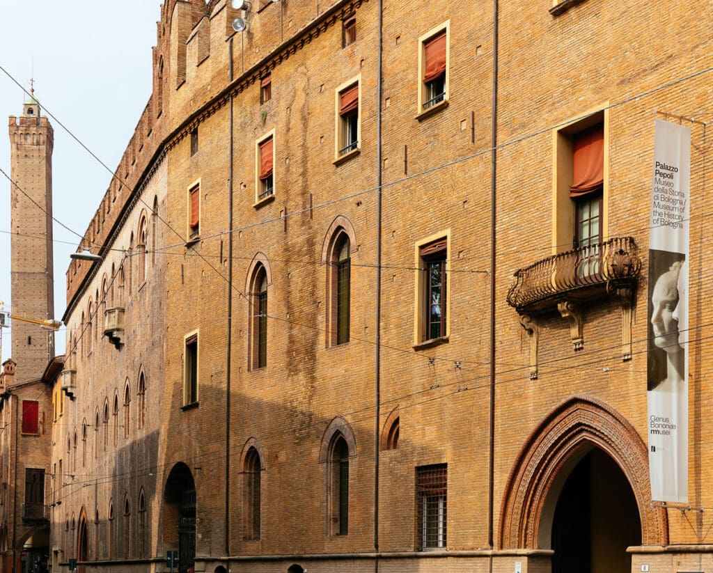 Historic building with arched windows, balcony, banner identifying Palazzo Pepoli Museum of Bologna