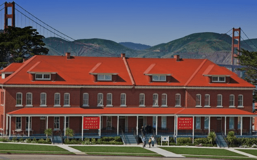 Red-roofed brick building named "The Walt Disney Family Museum" with the Golden Gate Bridge in the background.