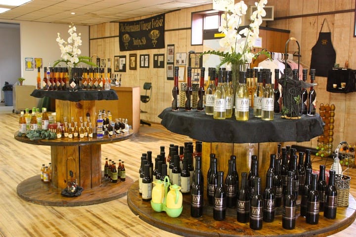 A store interior with wooden tables displaying various bottled products and decorative white flowers.
